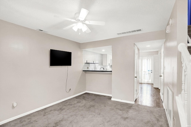 unfurnished living room featuring carpet, visible vents, ceiling fan, and baseboards