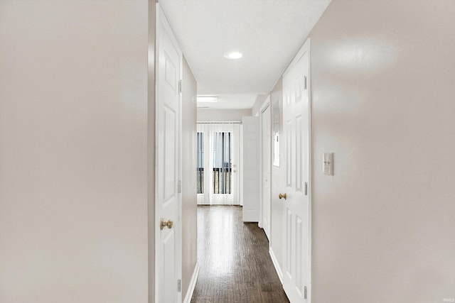 corridor with dark wood-type flooring and baseboards