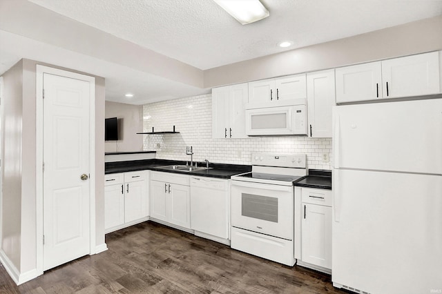 kitchen with white appliances, dark wood-style flooring, a sink, white cabinets, and dark countertops