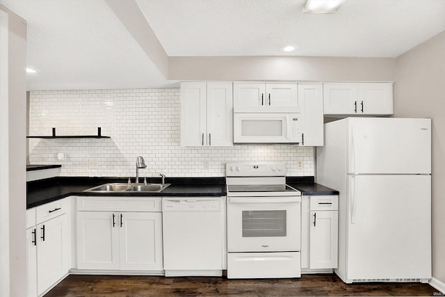 kitchen with white appliances, decorative backsplash, white cabinets, dark countertops, and a sink