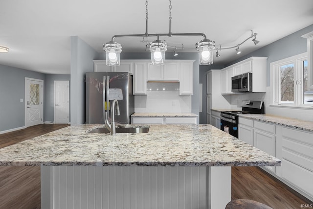 kitchen featuring dark wood-style flooring, appliances with stainless steel finishes, white cabinets, a kitchen island with sink, and a sink