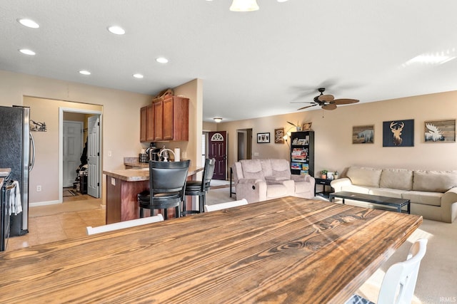 kitchen with brown cabinetry, freestanding refrigerator, open floor plan, and recessed lighting