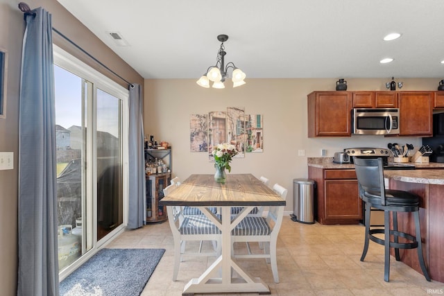 kitchen with pendant lighting, light countertops, stainless steel microwave, and brown cabinets