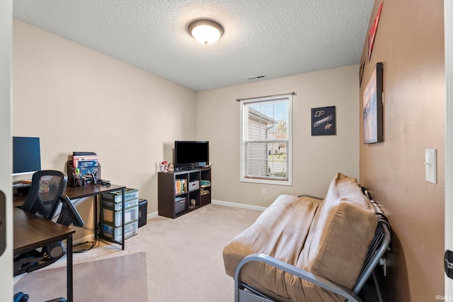 office featuring visible vents, light carpet, baseboards, and a textured ceiling