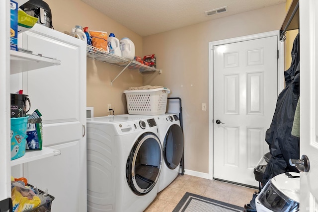 clothes washing area featuring light tile patterned floors, visible vents, a textured ceiling, washer and dryer, and laundry area