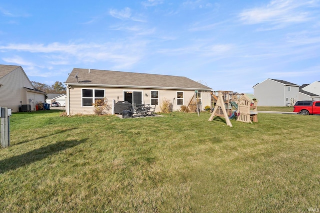 rear view of house with a playground, a yard, and central AC unit