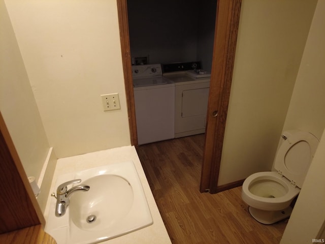 bathroom featuring toilet, washer and clothes dryer, a sink, and wood finished floors