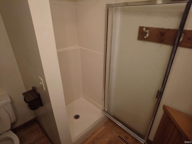 bathroom featuring toilet, a shower stall, and wood finished floors