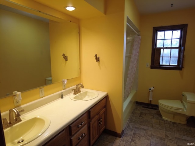 bathroom featuring stone finish floor, baseboards, a sink, and toilet