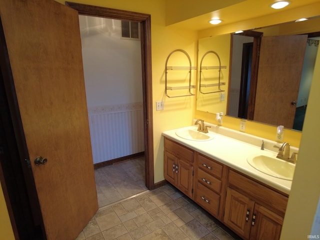 bathroom featuring double vanity, a wainscoted wall, visible vents, and a sink