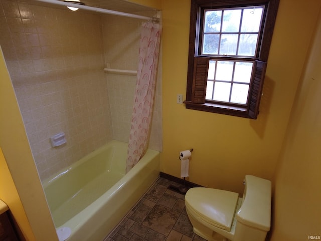 full bathroom with toilet, baseboards, stone finish floor, and shower / bath combo with shower curtain