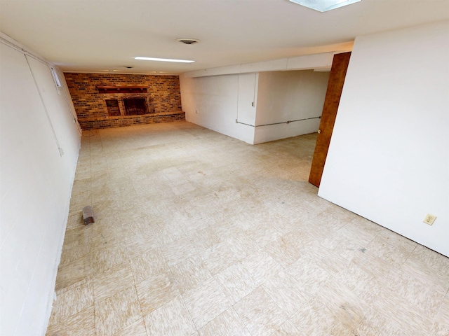 interior space featuring a brick fireplace, brick wall, visible vents, and light floors