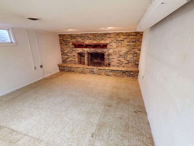 basement featuring brick wall, a brick fireplace, visible vents, and tile patterned floors