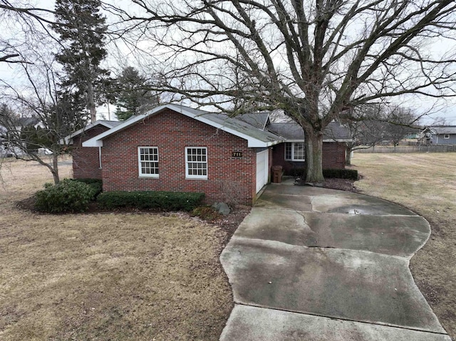 view of property exterior featuring a garage, brick siding, fence, concrete driveway, and a yard