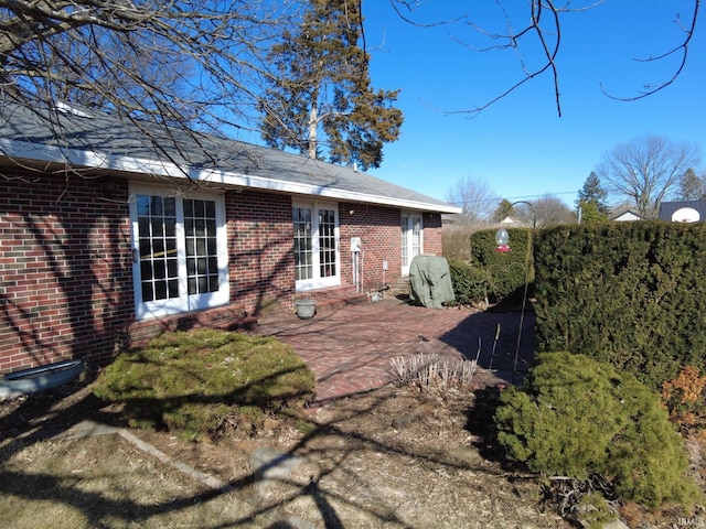 back of property with entry steps, brick siding, a patio area, and fence