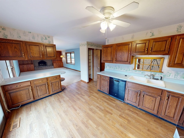 kitchen with a sink, black dishwasher, light countertops, brown cabinets, and light wood finished floors