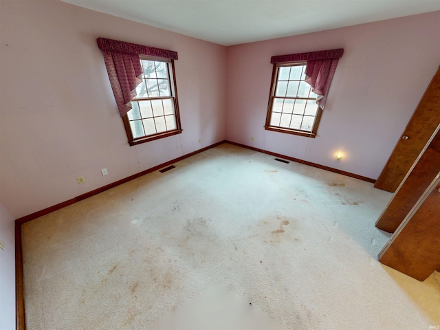 carpeted empty room with visible vents, plenty of natural light, and baseboards