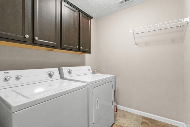 clothes washing area with visible vents, cabinet space, a textured ceiling, independent washer and dryer, and baseboards