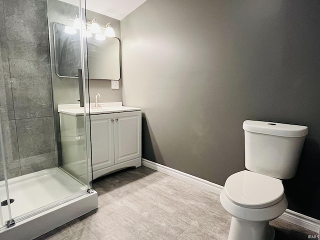 full bathroom with toilet, a shower stall, baseboards, and vanity