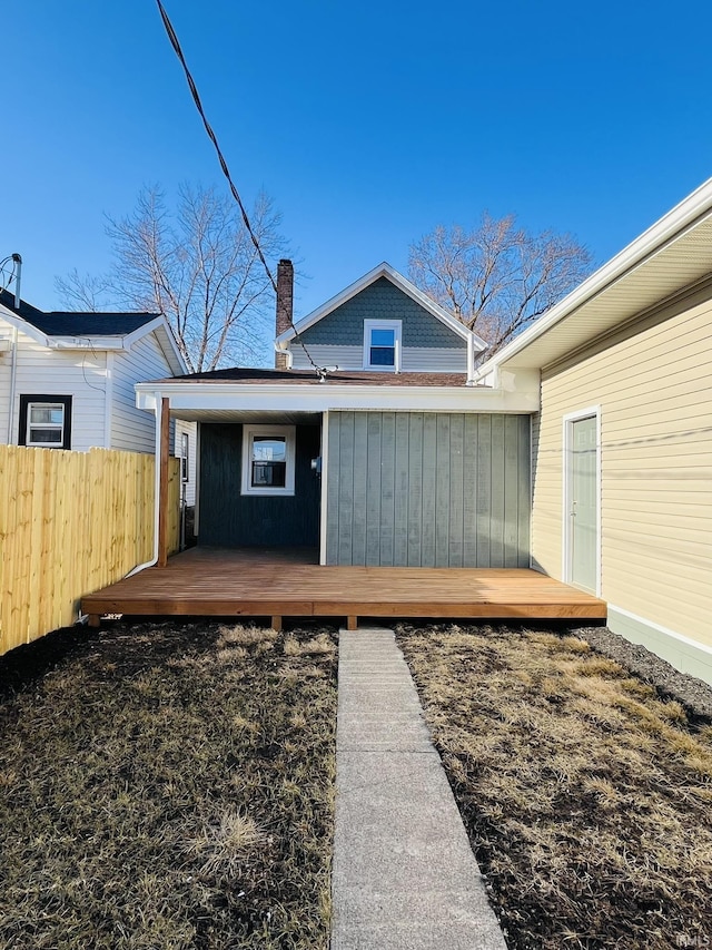 back of property with a chimney and fence