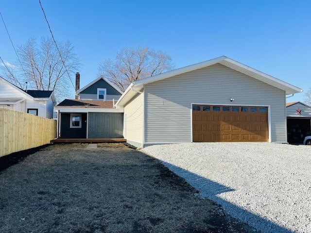 view of property exterior with an outbuilding, a detached garage, and fence