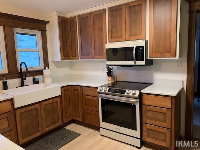 kitchen with a sink, stainless steel appliances, light wood-style flooring, and light countertops