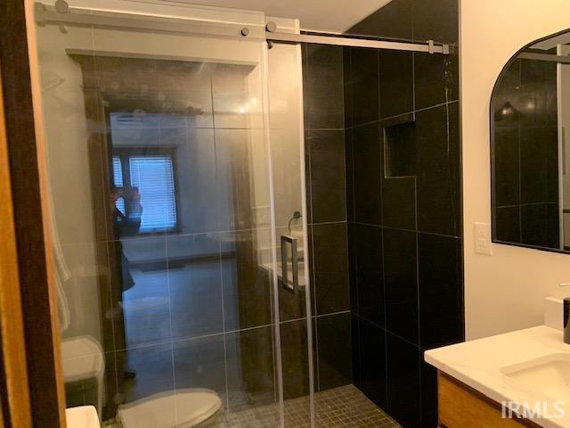 full bathroom featuring a shower stall, toilet, and vanity