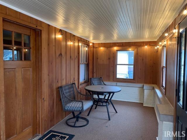 sitting room with wooden walls, wooden ceiling, and carpet floors