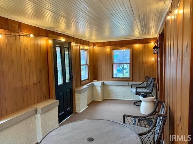 living area with carpet floors, wooden walls, and wood ceiling