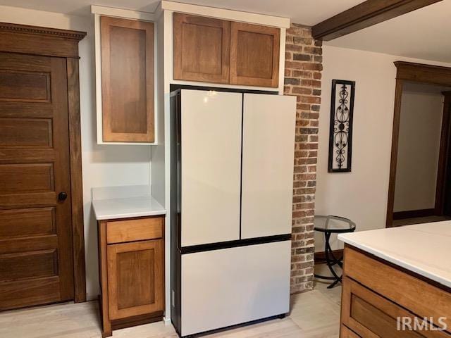 kitchen with light countertops, brown cabinets, and freestanding refrigerator