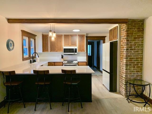 kitchen featuring a sink, freestanding refrigerator, a peninsula, light countertops, and stainless steel electric range oven