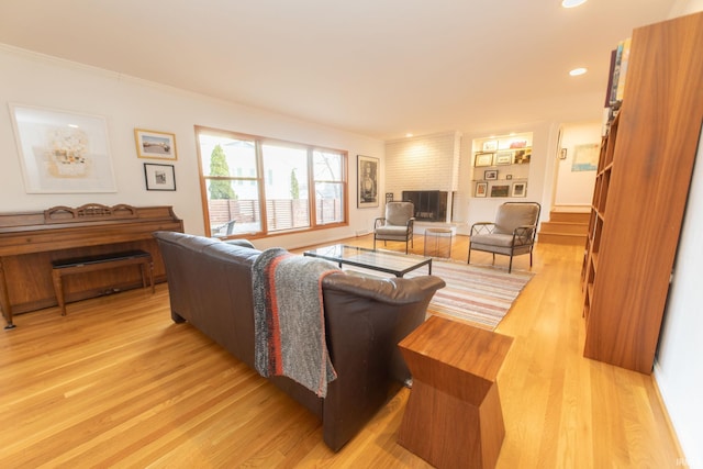 living room featuring a fireplace, recessed lighting, stairway, ornamental molding, and light wood-type flooring