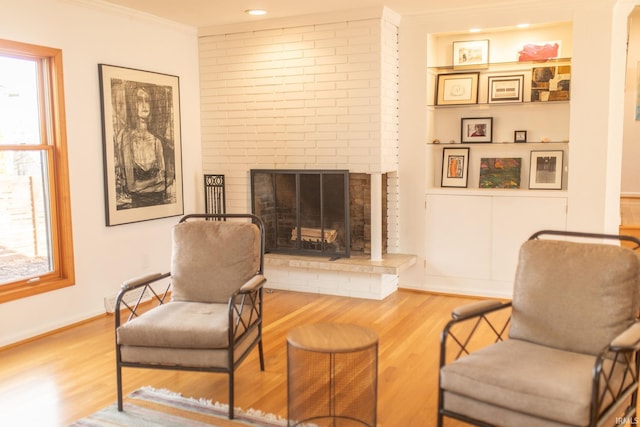 sitting room with crown molding, a fireplace, baseboards, and wood finished floors