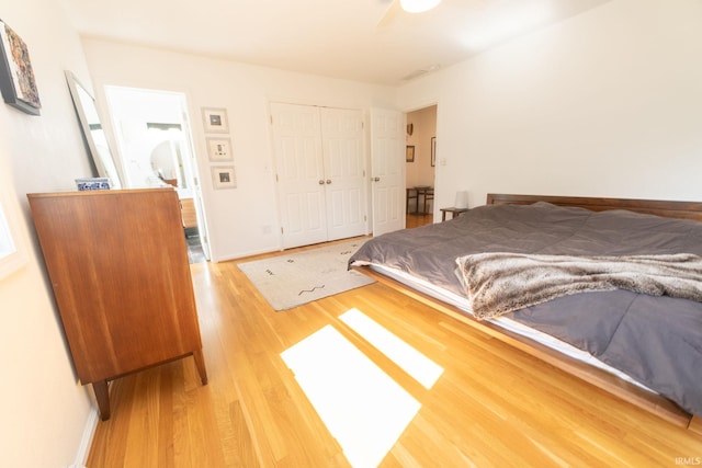 bedroom with a closet, light wood-type flooring, and baseboards