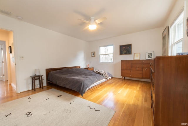 bedroom featuring light wood-style flooring, visible vents, ceiling fan, and baseboards