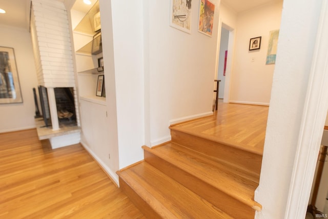 stairway featuring a fireplace, baseboards, and wood finished floors