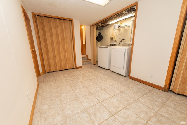 clothes washing area featuring baseboards, laundry area, light floors, and washer and dryer