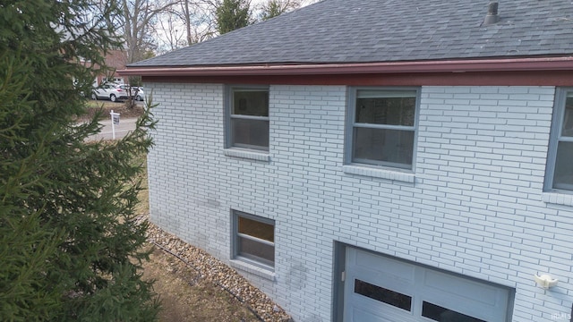 view of property exterior with brick siding and roof with shingles