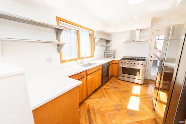 kitchen with appliances with stainless steel finishes, plenty of natural light, a sink, and wall chimney exhaust hood