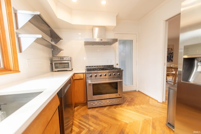 kitchen with tasteful backsplash, light countertops, appliances with stainless steel finishes, brown cabinetry, and wall chimney exhaust hood