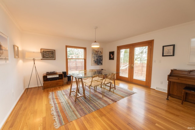 dining room with light wood-style floors, plenty of natural light, ornamental molding, and french doors