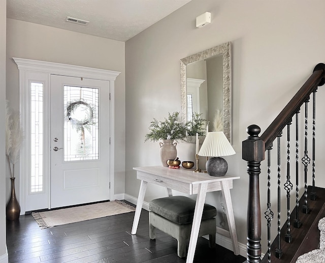 foyer entrance with a textured ceiling, stairs, baseboards, and hardwood / wood-style floors