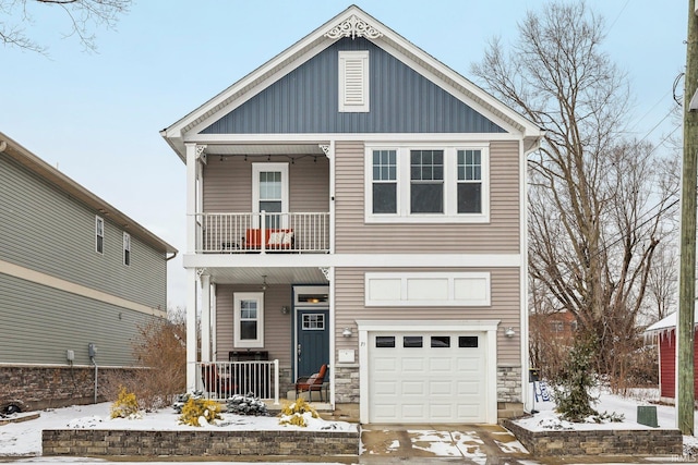 view of front of house with a balcony, covered porch, an attached garage, and stone siding