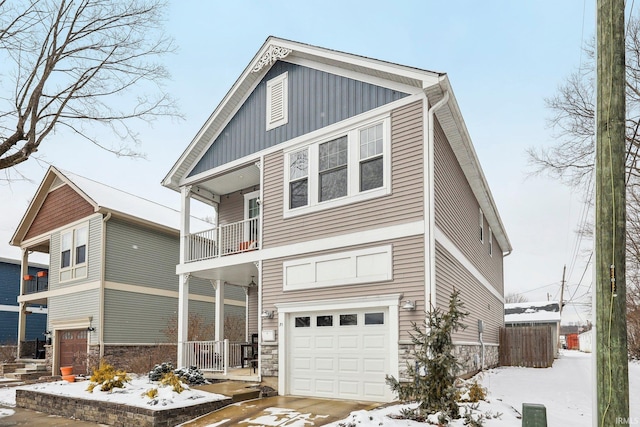 view of front of home with a garage, stone siding, a balcony, and board and batten siding