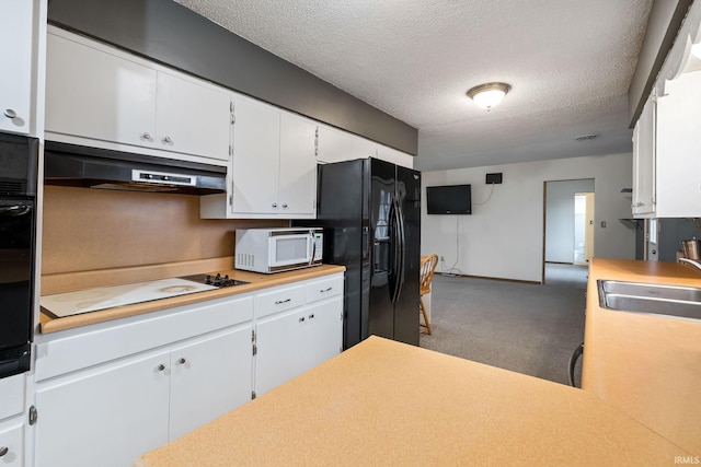 kitchen with under cabinet range hood, light countertops, carpet flooring, black appliances, and a sink