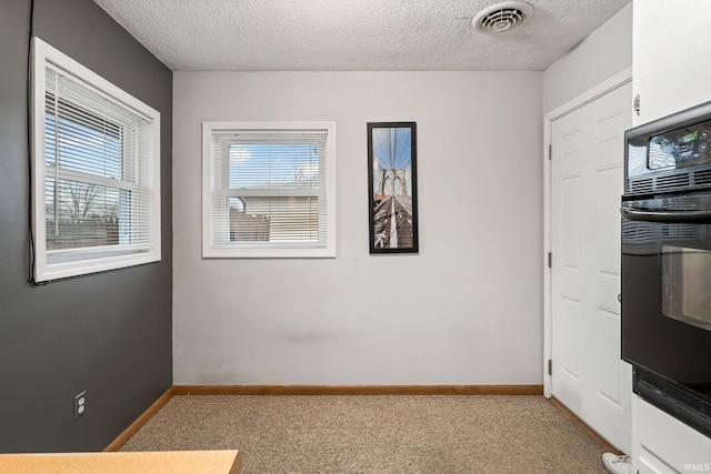 interior space with baseboards, visible vents, a textured ceiling, and light colored carpet