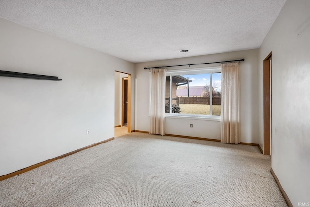 empty room featuring light carpet, visible vents, baseboards, and a textured ceiling