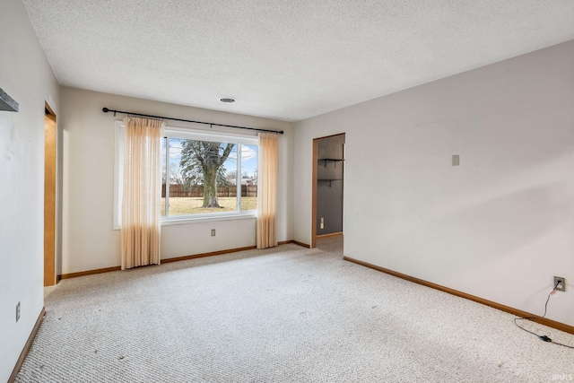 spare room with a textured ceiling, baseboards, and carpet flooring