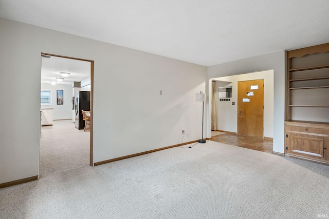 unfurnished living room featuring carpet flooring, built in features, and baseboards