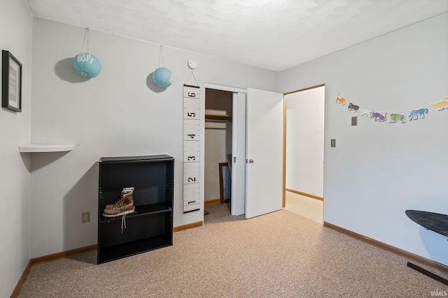 carpeted bedroom featuring a closet and baseboards